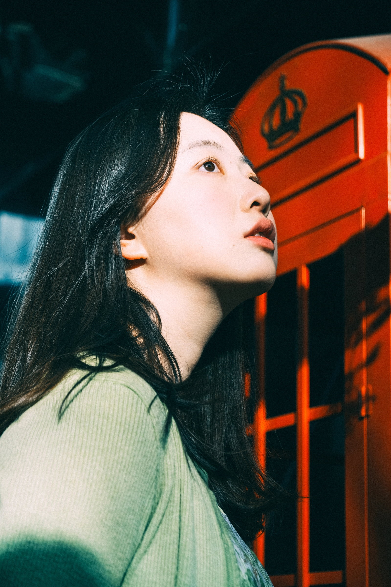 年轻女子在红色电话亭前抬头看向光线